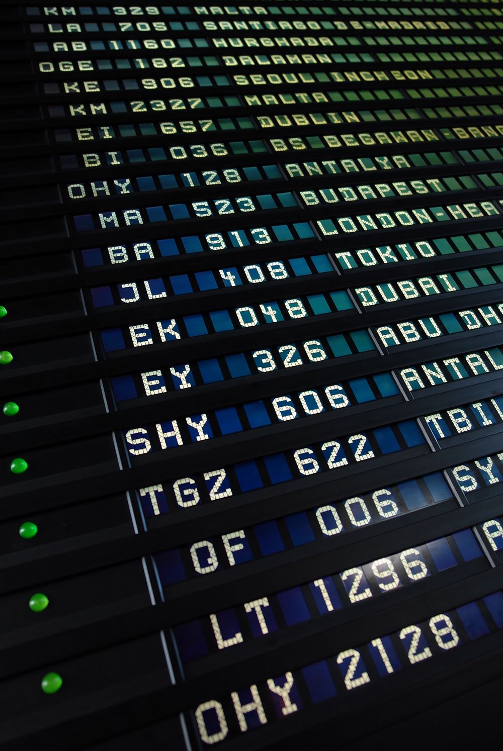 Airport split-flap departure board listing flights to London Heathrow, Tokyo, Dubai and Antalya