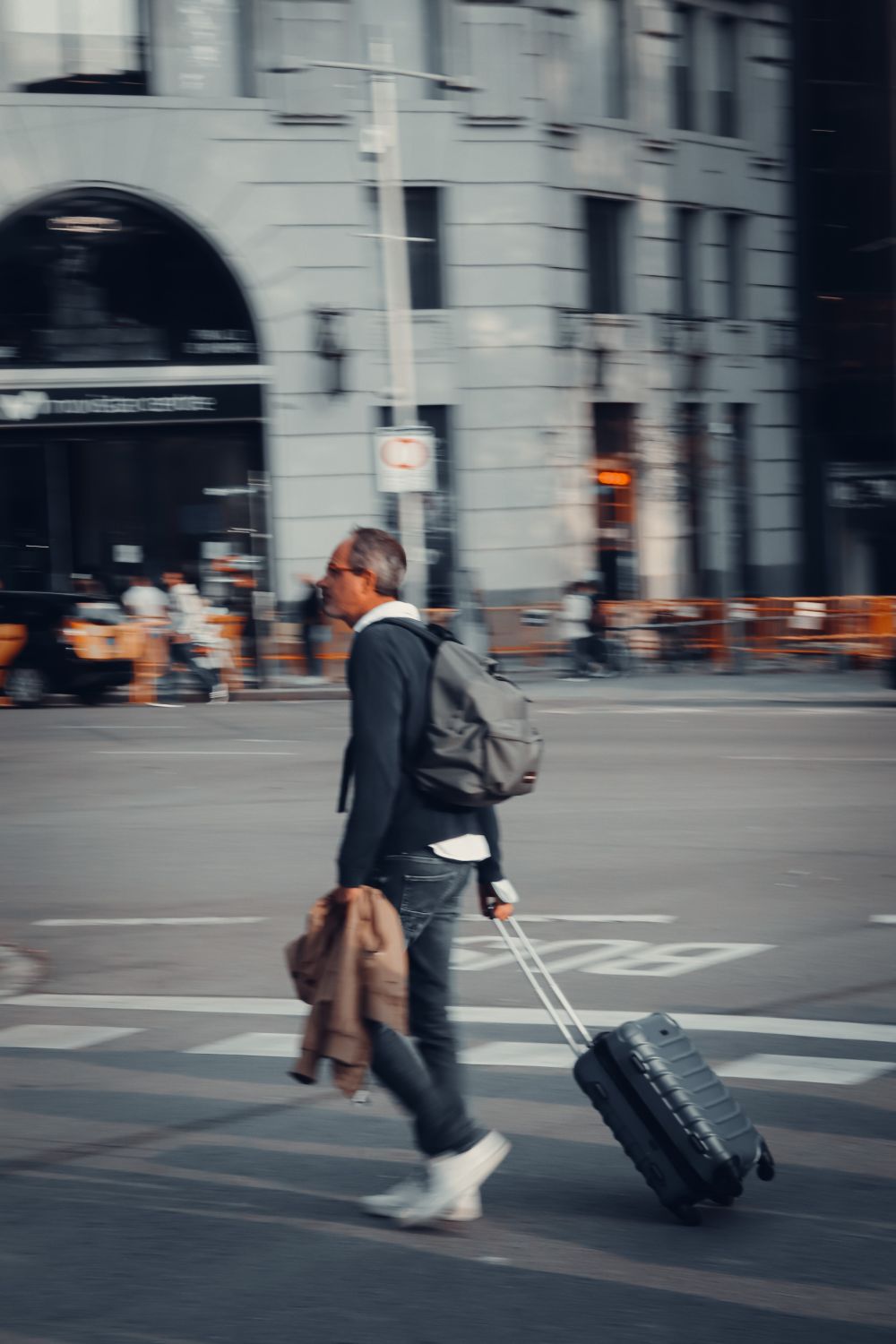 A business traveller carrying a backpack walking along a busy city street