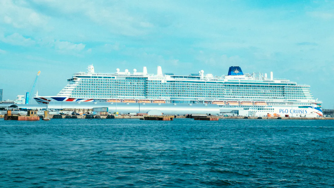 A white cruise ship berthed under a bright blue sky